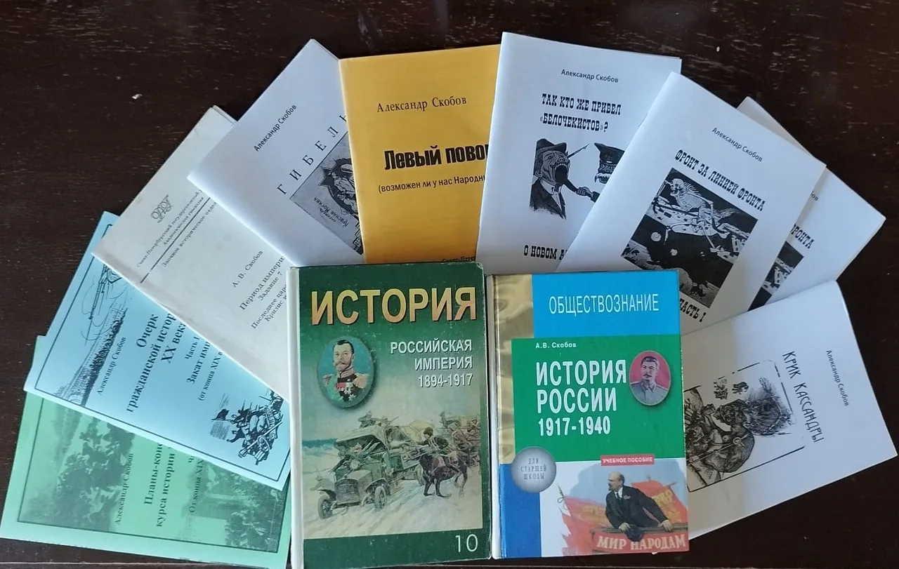 Книги и брошюры разложены веером на тёмной поверхности.