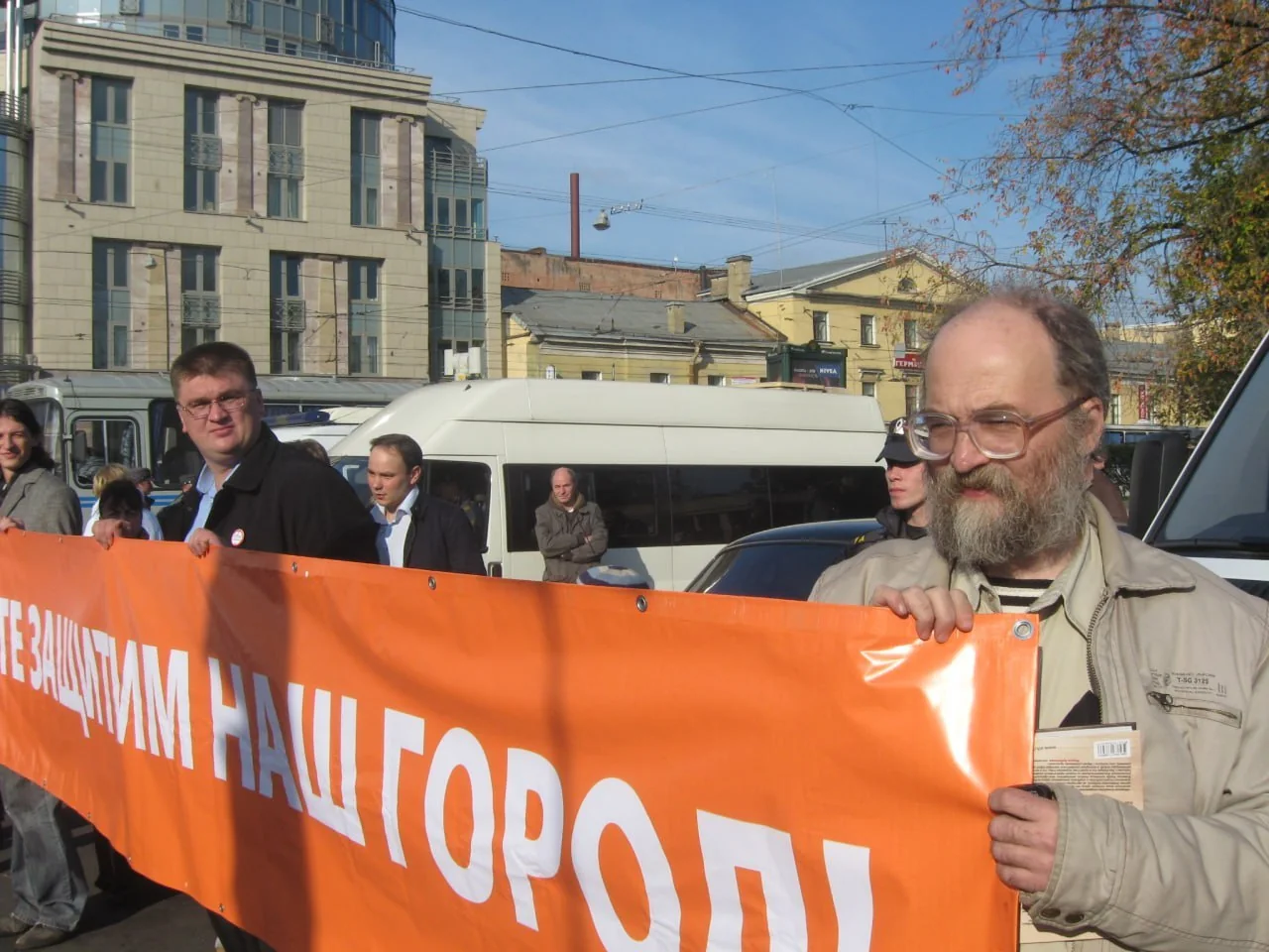 Александр Скобов держит оранжевый баннер на городской акции.