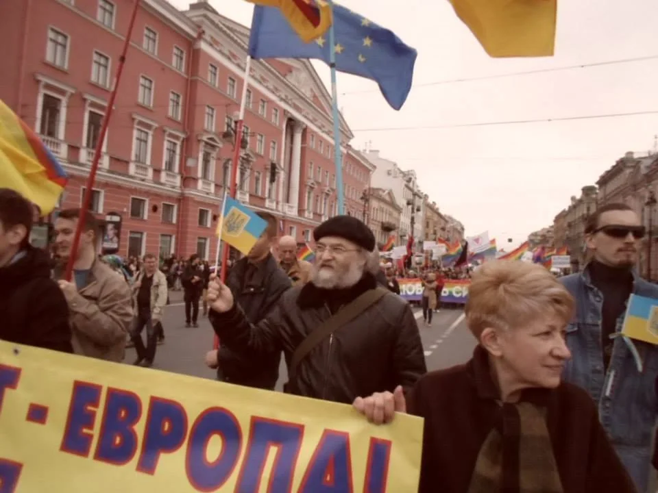 Александр Скобов идёт на марше рядом с плакатом «Европа» и флагами Украины.