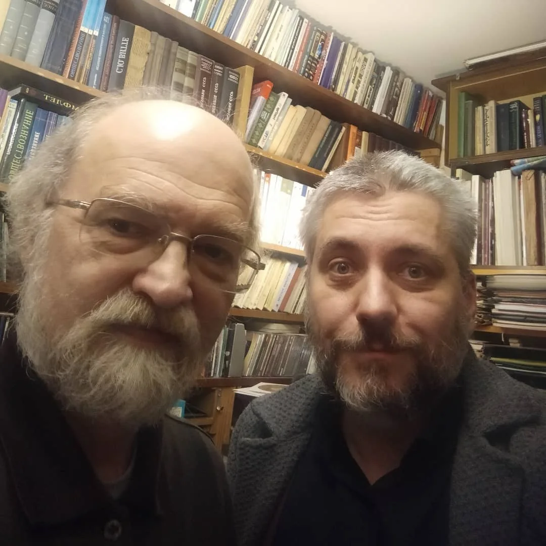 Александр Скобов и Владимир Волохонский крупным планом на фоне книжных полок.